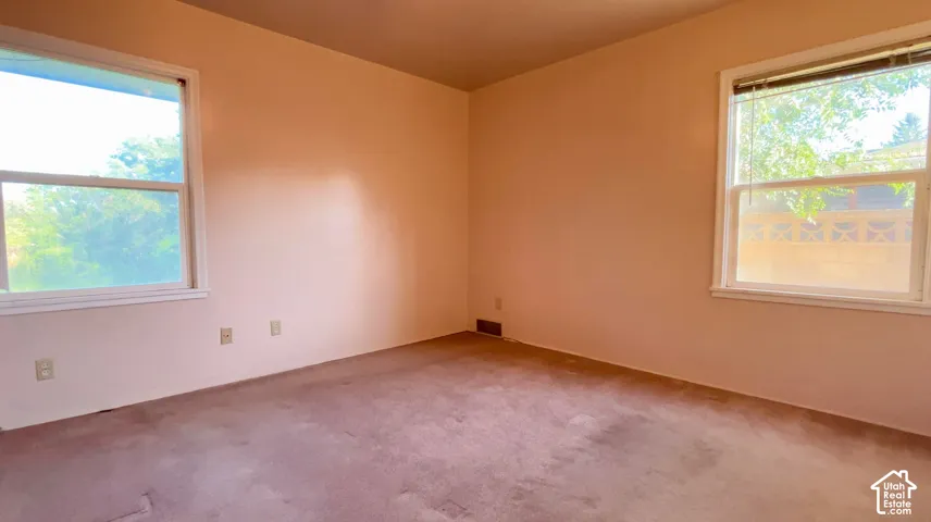 Two windows with white trim, wall-to-wall carpeting, and neutral wall paint