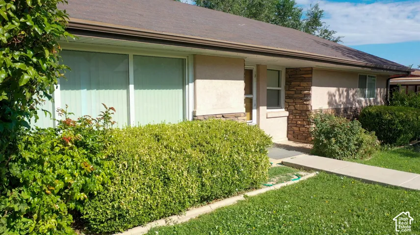 Stucco exterior with stone accents, brown roof, and front landscaping
