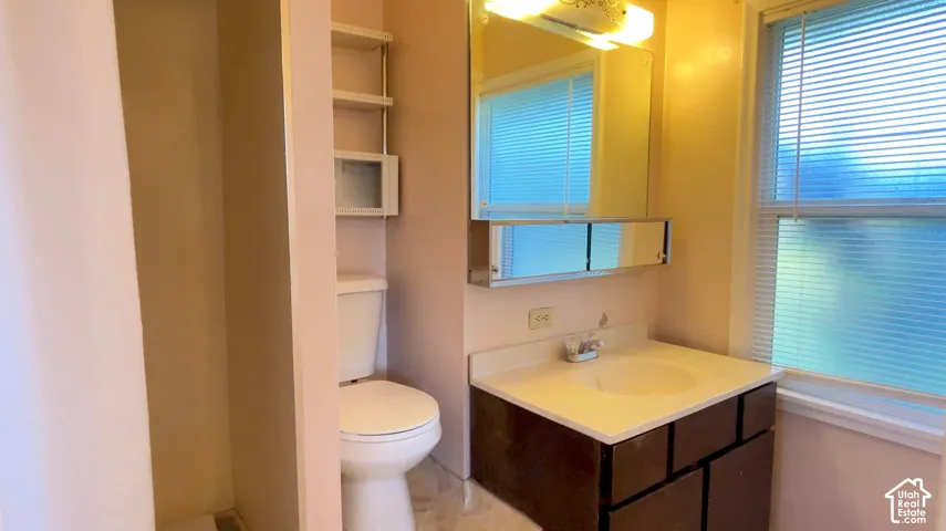 Recessed shelving unit, built-in medicine cabinet, single vanity with integrated sink, window with blinds, and overhead lighting