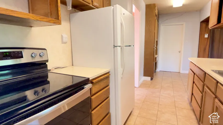 Tiled flooring, wood cabinetry, built-in appliances, and light-toned countertops