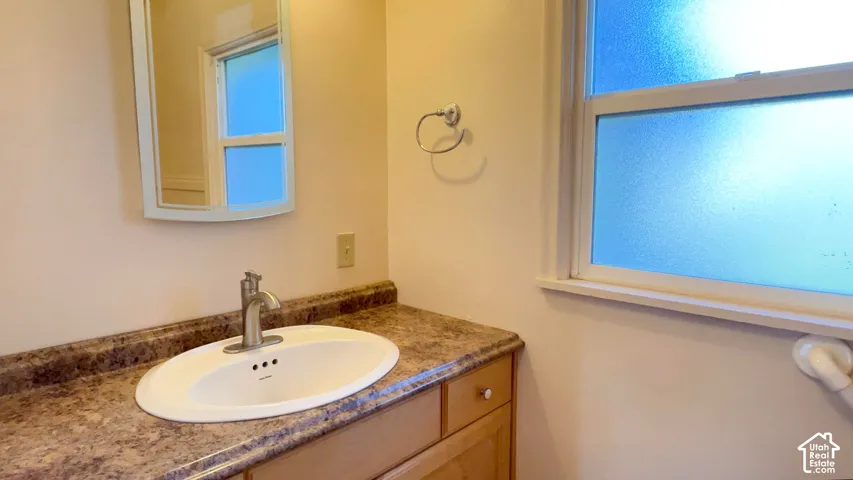 Vanity with integrated sink, brushed nickel faucet, and wood-finish cabinetry