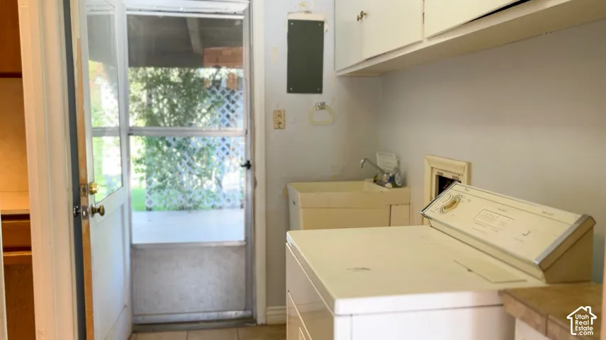 Laundry area with upper cabinetry, utility sink, and tile flooring