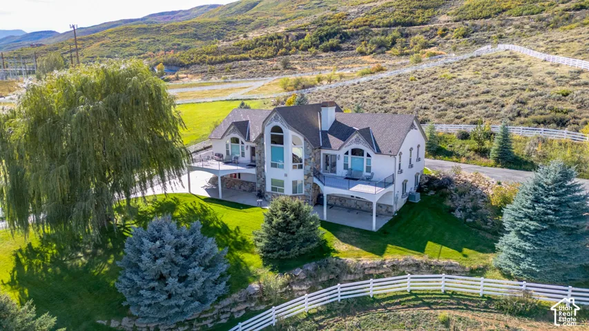Stone and stucco exterior residence featuring a multi-level covered patio and an upper-level balcony