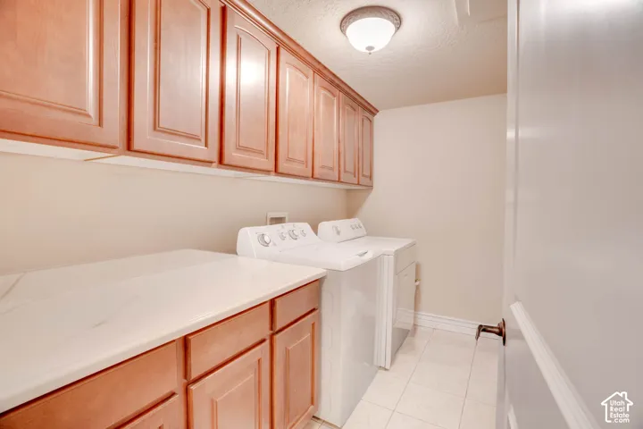 Wood-finish cabinetry with white countertops, overhead ceiling light, and tile flooring