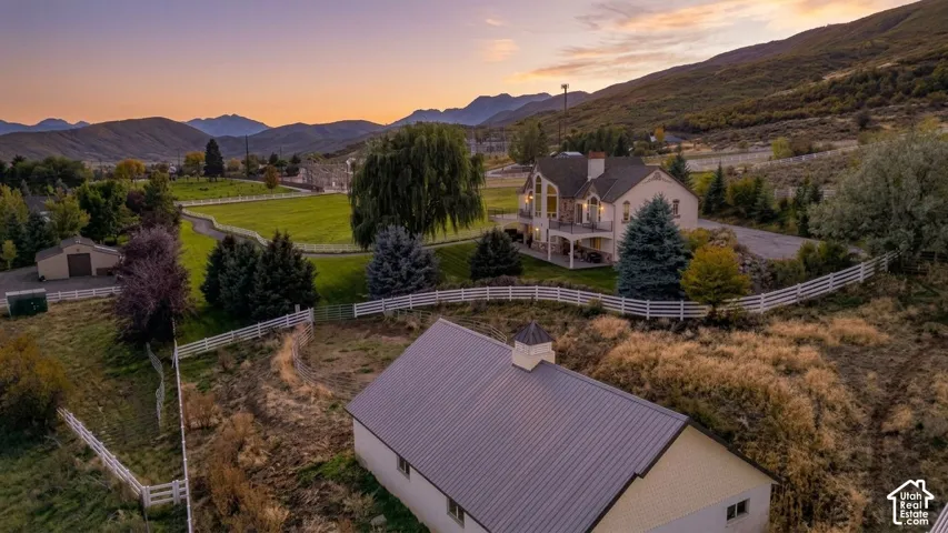 Expansive property featuring a central residence with a balcony, multiple outbuildings, and white fencing