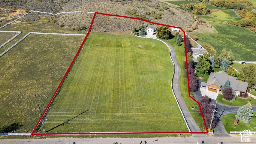 Expansive land parcel featuring a paved private drive, mature trees, and a substantial grassy area