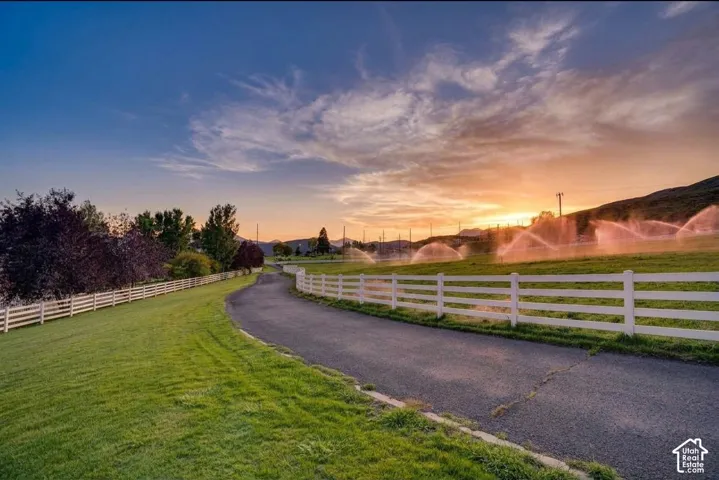 Paved driveway bordered by white fencing