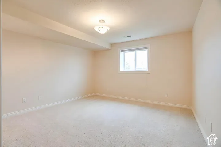 Recessed ceiling beam, light-colored carpet flooring, single window with white trim, flush mount ceiling light fixture, neutral wall color