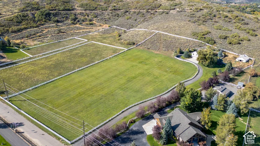 Expansive property featuring fenced pastures, mature landscaping, paved driveways, and multiple structures including a primary residence and outbuildings