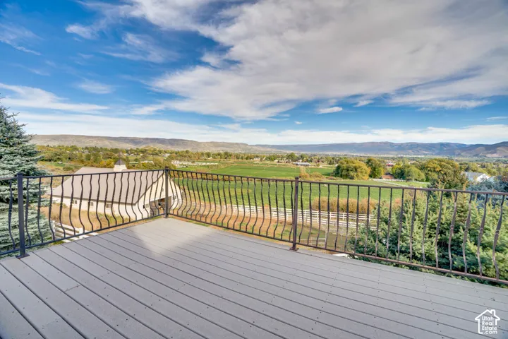 Expansive outdoor deck featuring composite decking, wrought iron railing, and distant mountain scenery