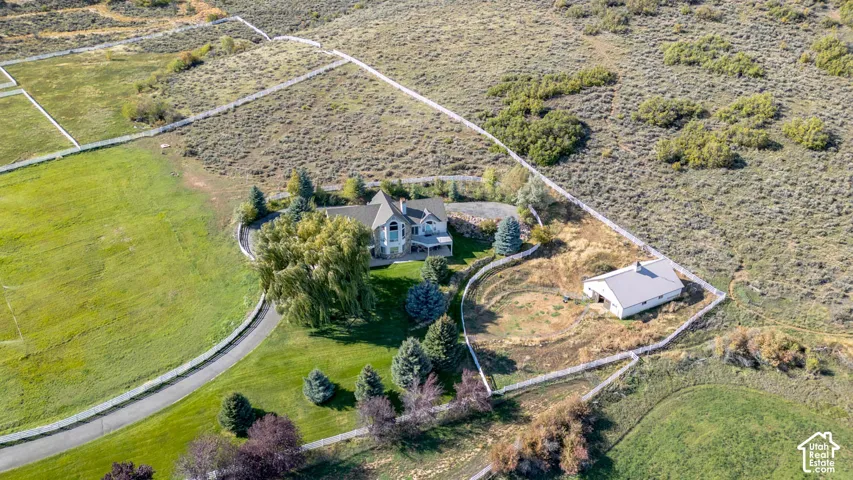 Expansive grounds featuring a main residence, paved driveway, detached outbuilding, and mature landscaping