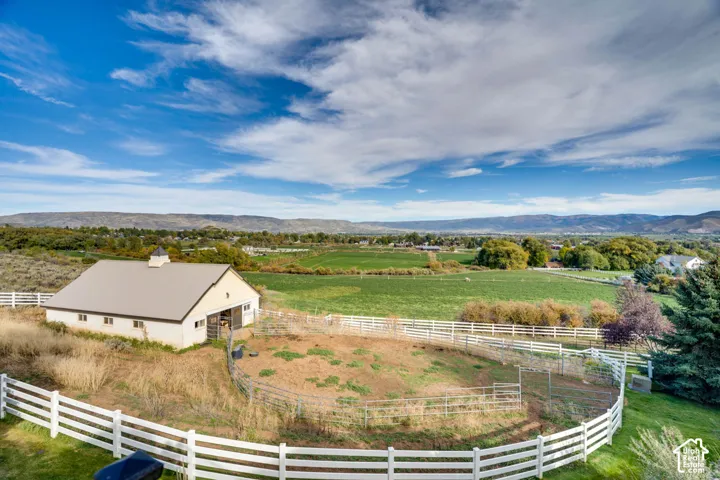 Expansive acreage featuring a white barn with a cupola, a fenced paddock, and a manicured lawn