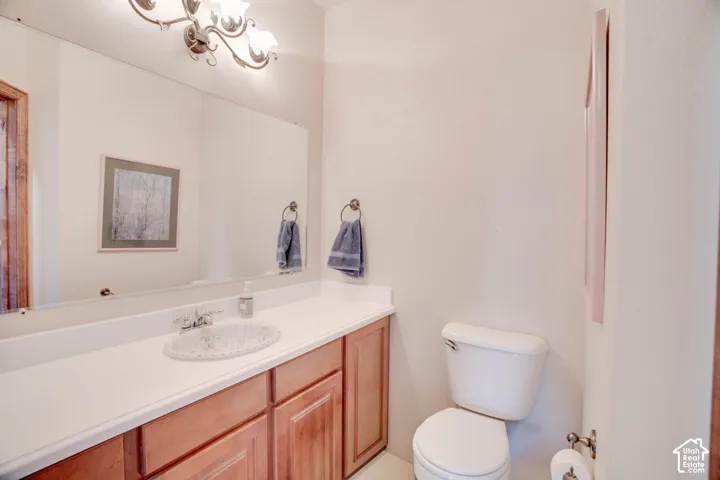 Bathroom featuring a vanity with a white countertop, wood-finish cabinetry, a drop-in sink, and a wall-mounted light fixture