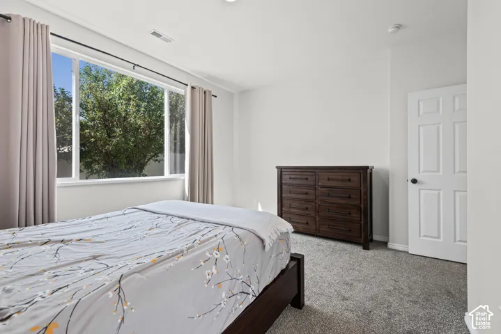 Spacious room featuring a large window, light-colored walls, and gray carpeting