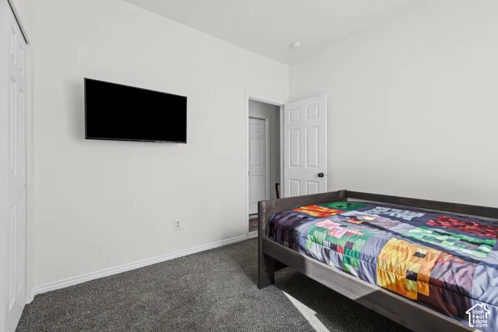 Wall-mounted television with a clean white wall, gray carpet, and white trim