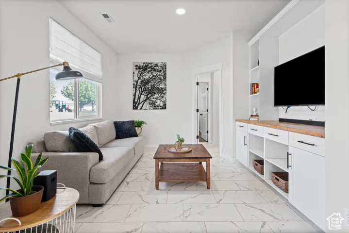 Recessed lighting, tile flooring, built-in cabinetry with wood-finish countertop, white window treatments, and white walls
