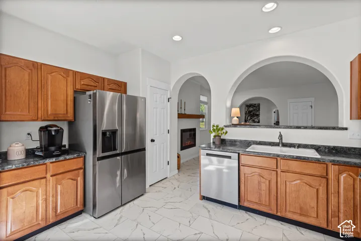 Kitchen featuring wood cabinetry, stainless steel appliances, and a pass-through with arched openings
