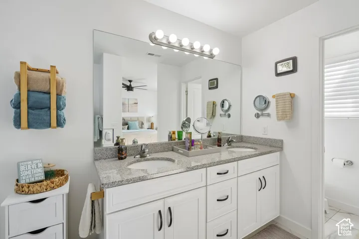 Dual vanity with undermount sinks, granite-style countertop, full-width mirror, and white cabinetry