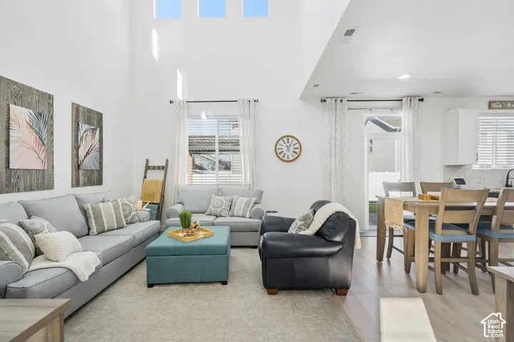 Vaulted ceilings with high windows, light wood-finish flooring, and a sliding glass door provide brightness