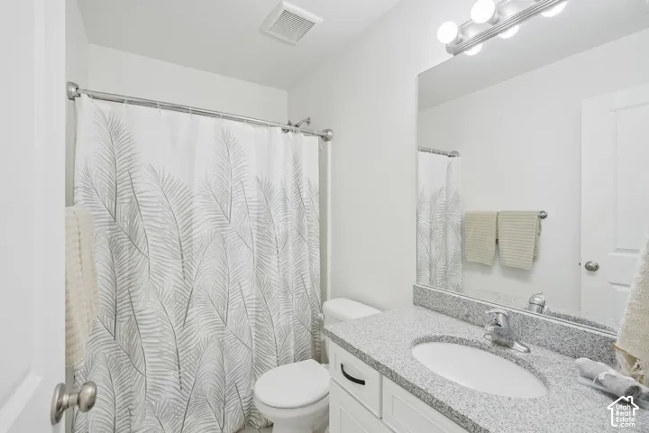 Bathroom featuring a single vanity with a light speckled countertop, an oval undermount sink, a chrome faucet, and a large wall-mounted mirror