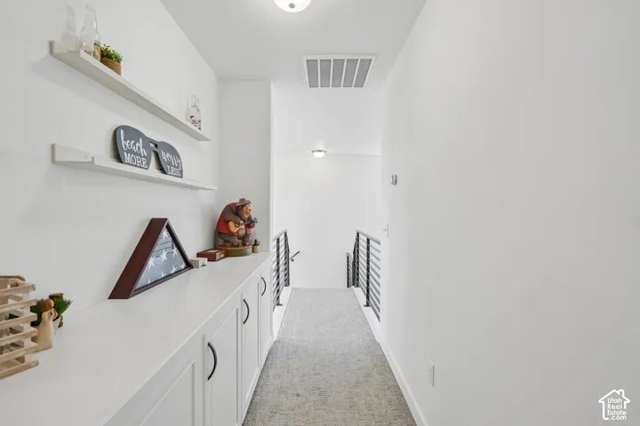 Hallway featuring built-in cabinetry, floating wall shelves, and a carpeted floor