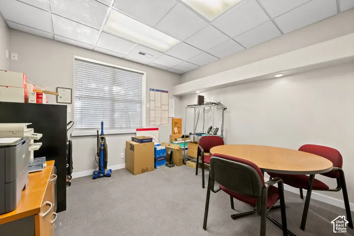 Recessed ceiling lighting, dropped ceiling, window with horizontal blinds, light gray wall paint, and gray carpet flooring