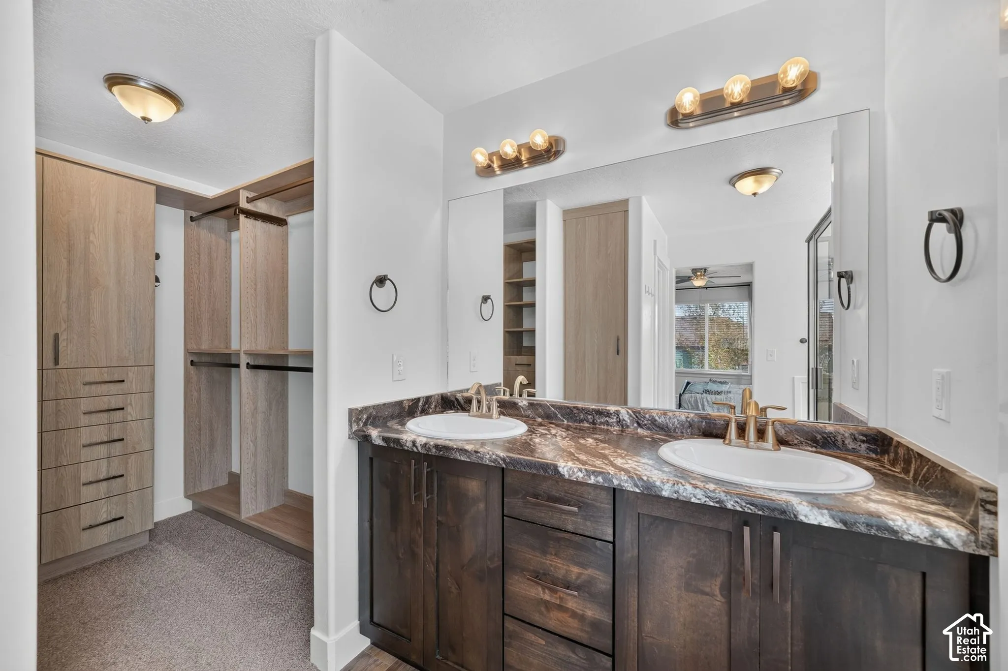 Double vanity with undermount sinks, wood-finish cabinetry, and a full-width wall mirror