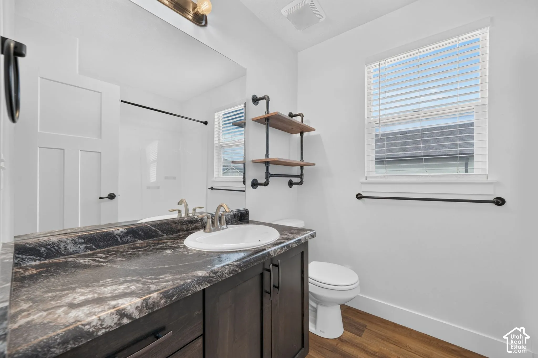 Vanity with integrated sink, dark wood-finish cabinetry, and patterned countertop