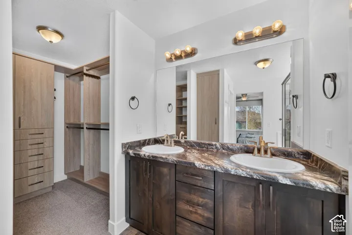 Double vanity with undermount sinks, wood-finish cabinetry, and a full-width wall mirror