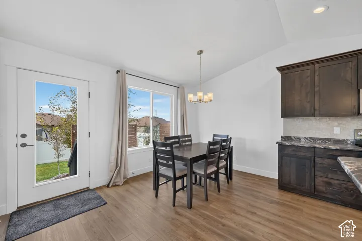 Wood-finish flooring, vaulted ceiling, built-in dark wood cabinetry, window with backyard views, and glass-paned exterior door
