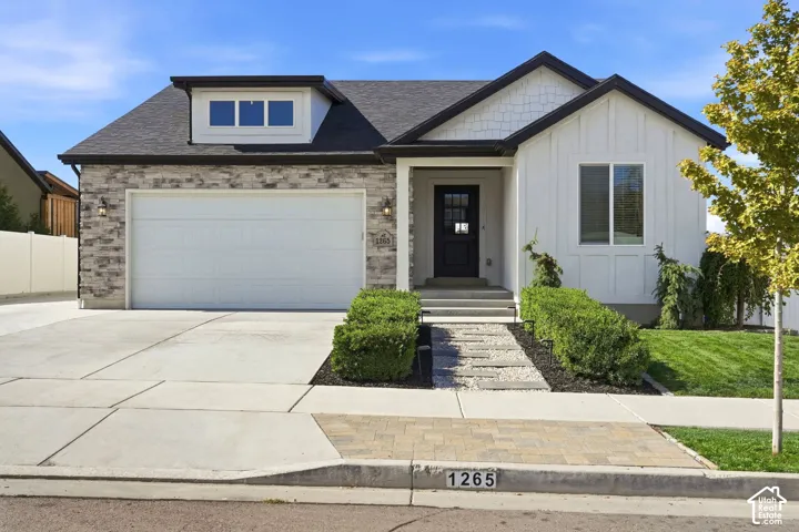 Stone veneer and vertical white siding exterior with a dark roof and trim