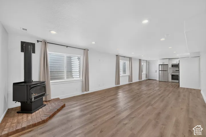 Wood-finish flooring throughout, recessed lighting, and a corner wood-burning stove with a brick hearth