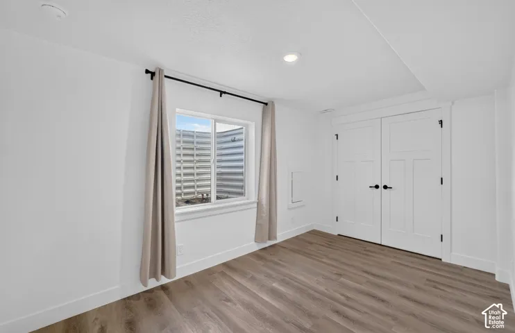 Recessed lighting, wood-finish flooring, white walls, white trim, and white paneled doors with matte black hardware