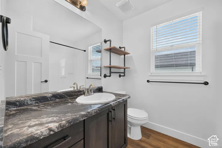 Vanity with integrated sink, dark wood-finish cabinetry, and patterned countertop