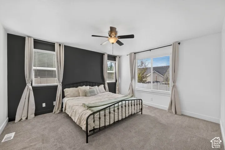 Recessed lighting, ceiling fan, dark accent wall, multiple windows, and neutral carpet flooring