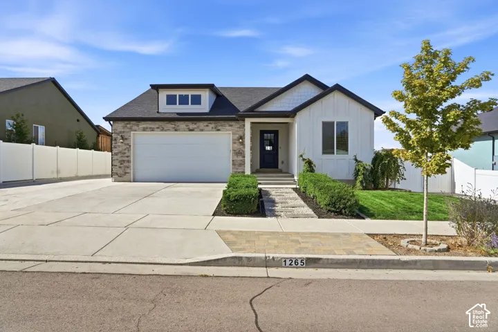Contemporary exterior with a stone and vertical siding facade, dormer window, two-car garage, and concrete driveway
