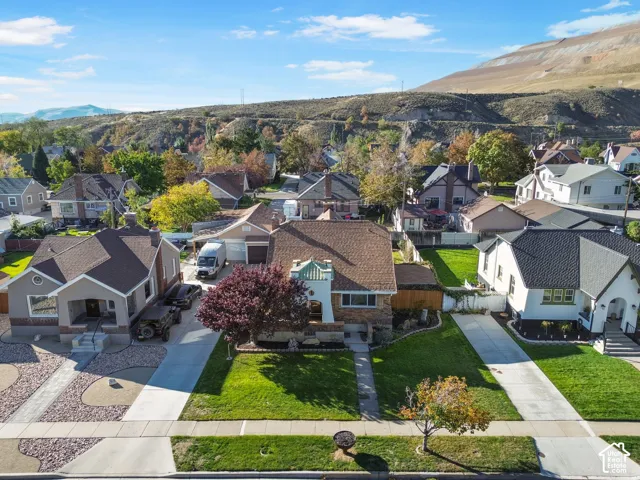 Well-manicured front lawn, mature trees and paved driveway