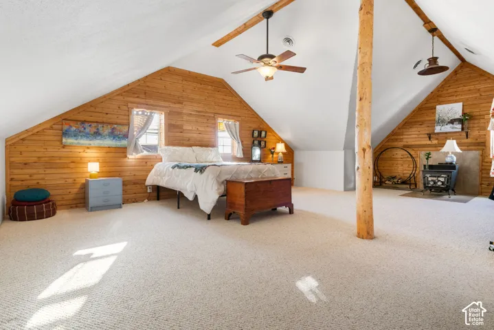 Large primary suit with vaulted ceiling, wood-paneled walls and exposed structural beam.
