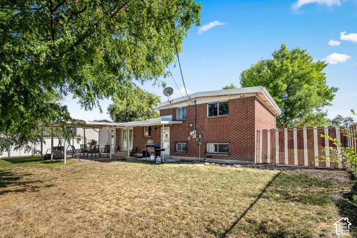 Brick exterior featuring multiple windows, a covered patio area, and a fenced yard