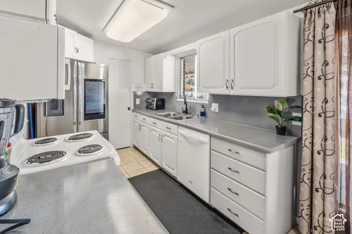 Kitchen featuring white cabinetry, gray countertops, stainless steel refrigerator, and tiled flooring