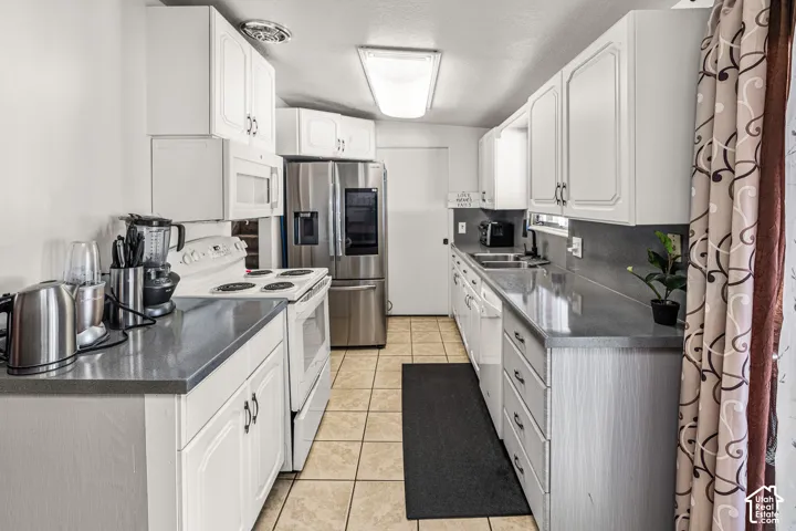Galley kitchen featuring white cabinetry, light countertops, integrated sink, and tile flooring