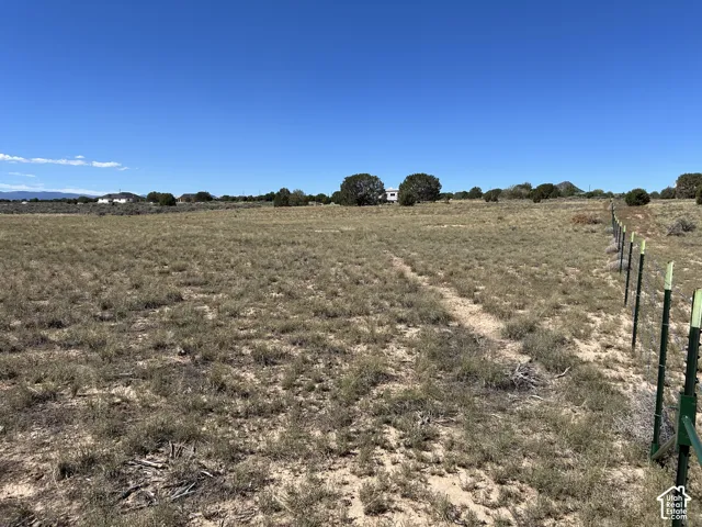 Expansive open land featuring natural vegetation and a partial fence line