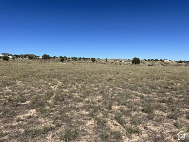 Expansive open terrain featuring natural vegetation and distant residential structures