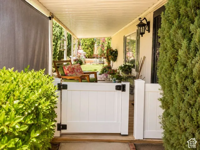 Covered patio with a corrugated metal ceiling, a decorative outdoor wall lantern, and a white wood-panel gate