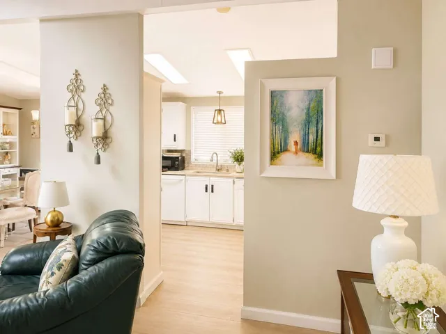 Recessed lighting, wood-finish flooring, white cabinetry, light-toned countertops, and a stainless steel sink