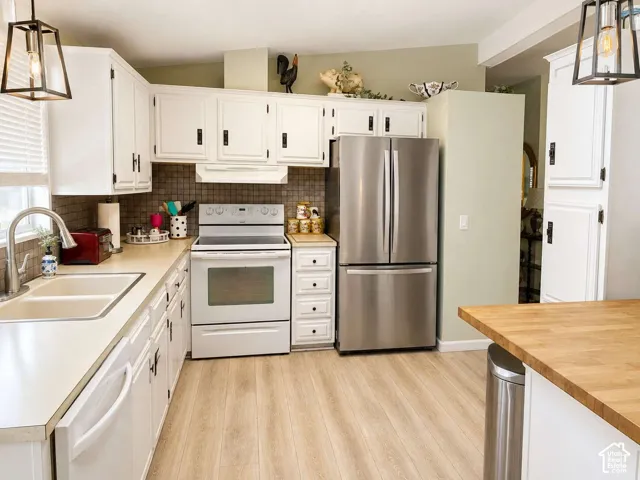 White cabinetry with black hardware, wood-finish flooring, stainless steel French door refrigerator, white electric range, and a dual basin sink with a gooseneck faucet
