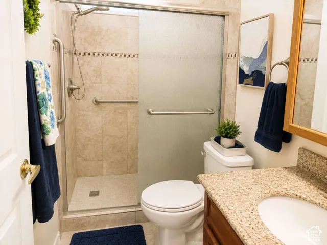 Walk-in shower with tiled surround and integrated grab bars, complemented by a wood-finish vanity with a light-colored countertop