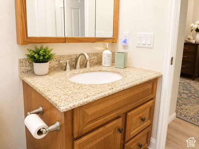 Wood-finish vanity with an integrated sink, granite-style countertop, and brushed nickel hardware
