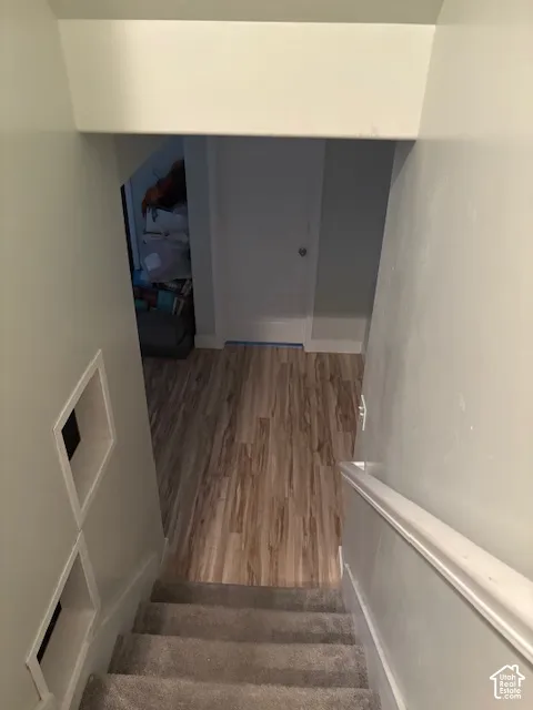Carpeted staircase with built-in wall niches, leading to wood-finish flooring and a solid white door