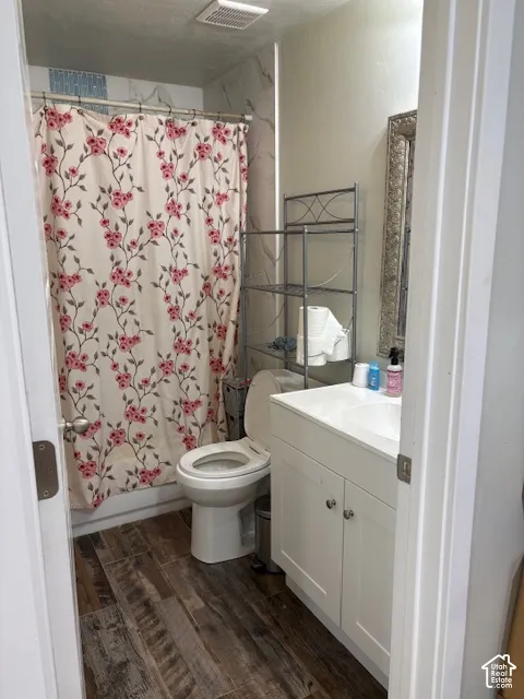 Wood-finish flooring, white vanity with integrated sink, and a built-in tub with tile surround